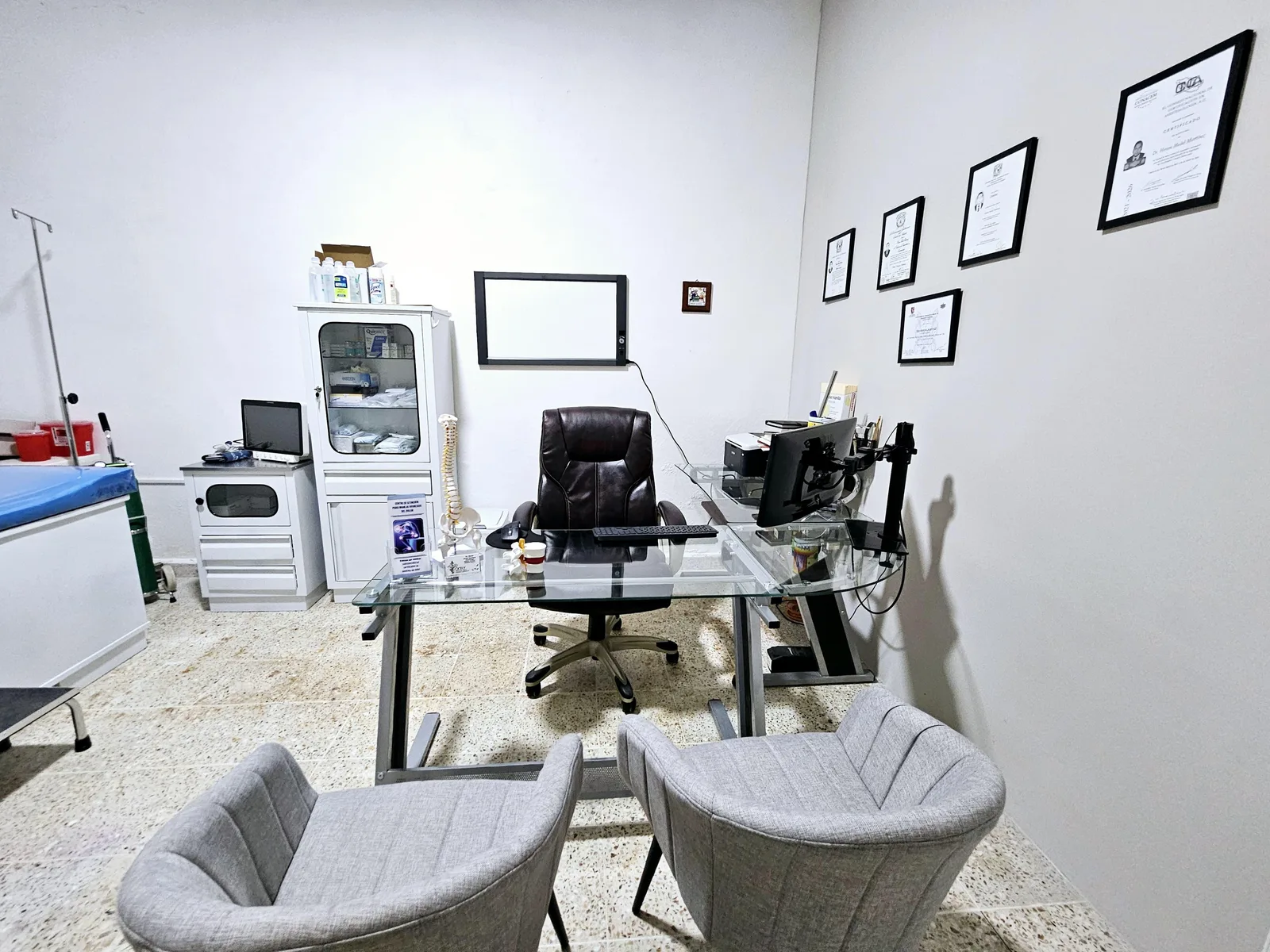 Escritorio del consultorio con certificaciones y diplomas del Dr. Hiram Medel en la pared